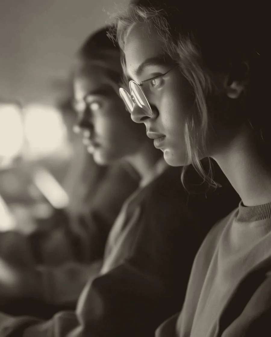 A stylized grey-scale close-up of two women working diligently on their computer.